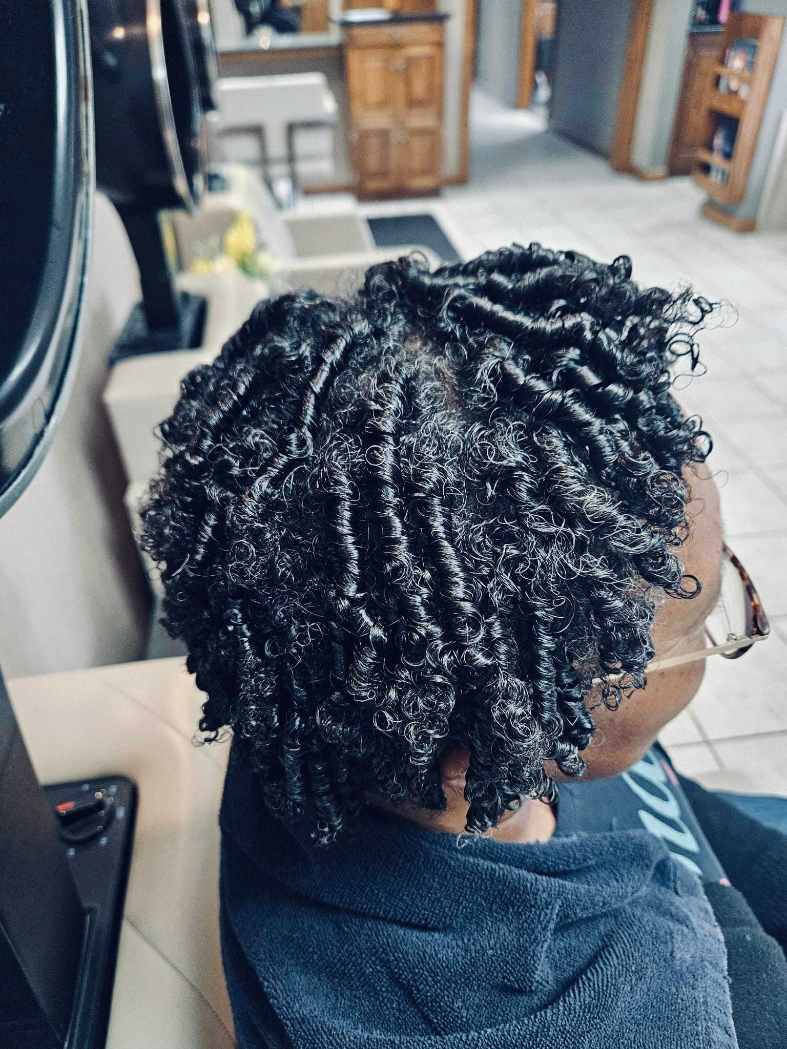 Woman with neatly styled twist curls in a salon setting.