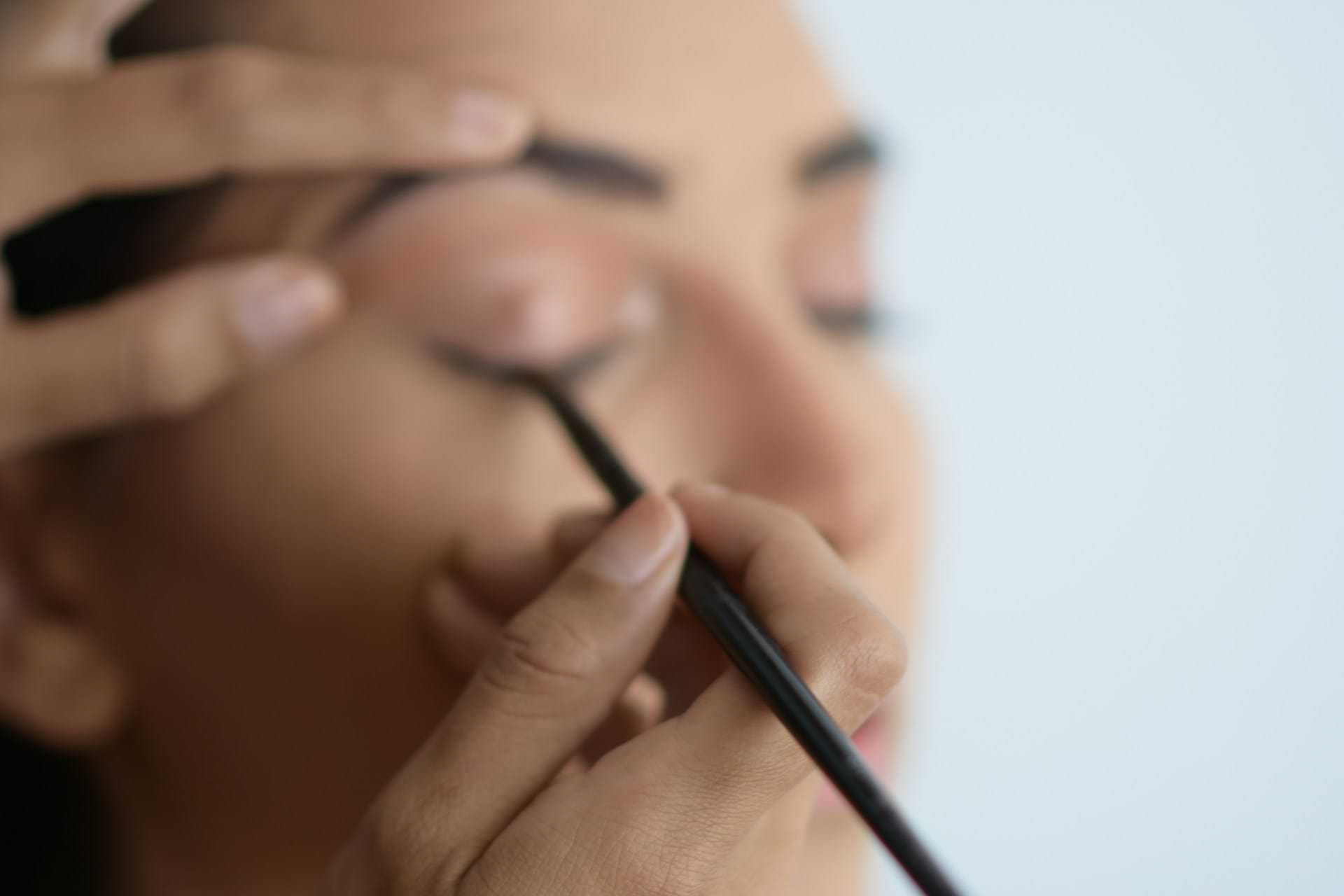 Close-up of a person applying eyeliner with precision, focusing on the eye area.